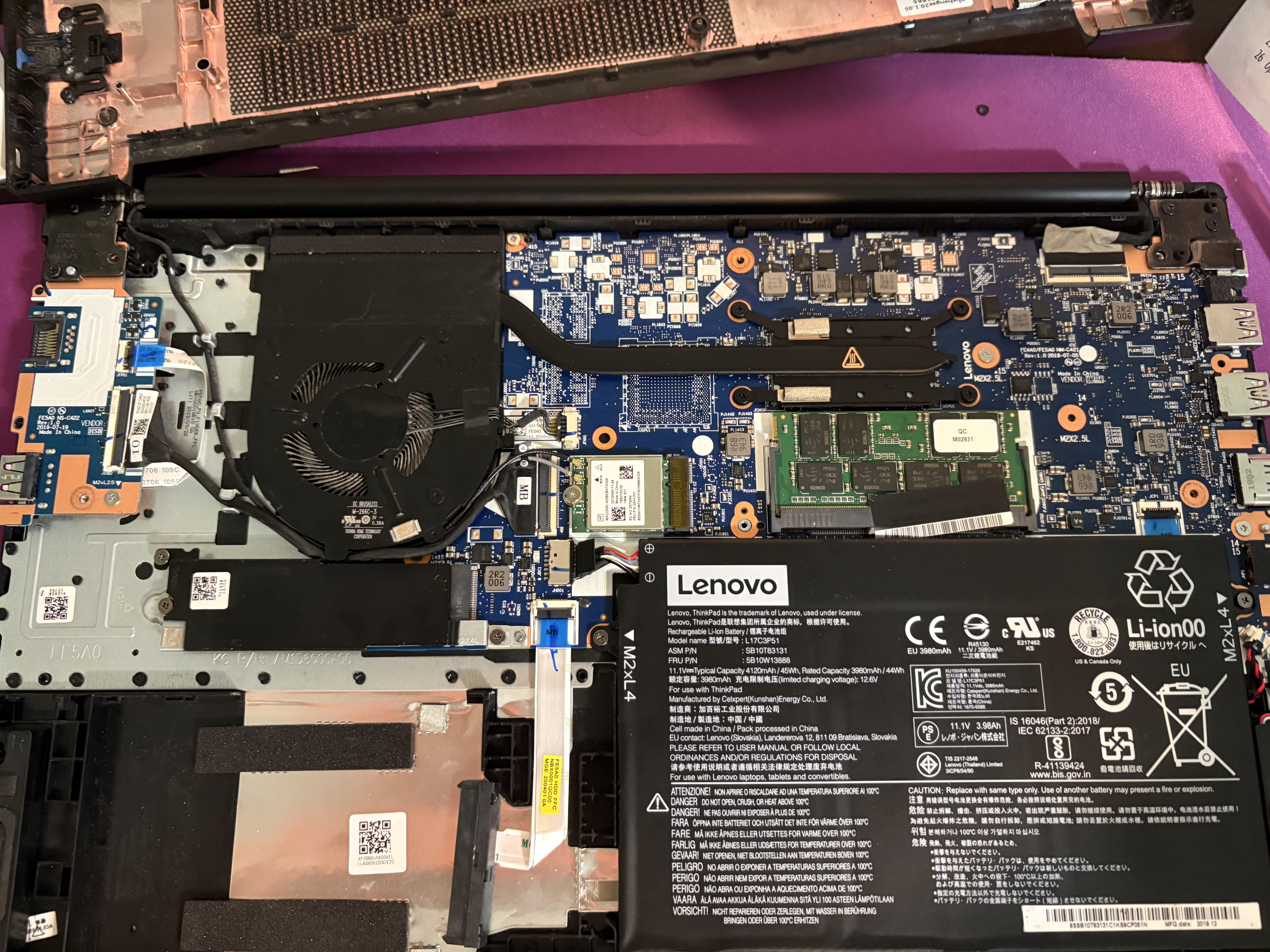 Lenovo laptop opened for repair, motherboard and battery visible